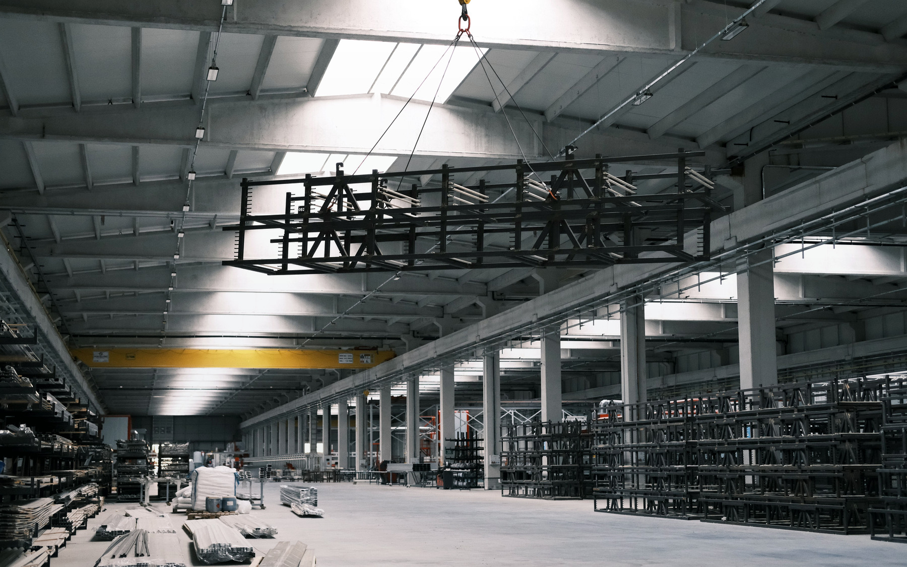Photographie d’une structure métallique suspendue par un pont roulant dans un atelier industriel